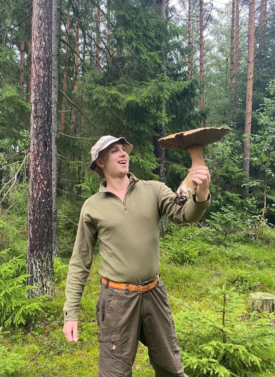 Martin Berggren Nilsen holder en stor sopp i barskog.